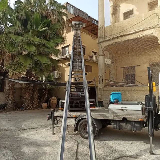 מנוף פרוס בחצר של בניין ישן בין עצי דקל
